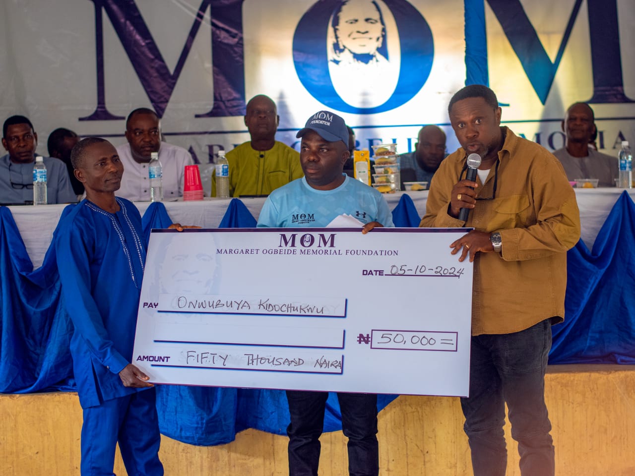 Hon Cosmas Igbenije presenting a cheque to one of the recipients.